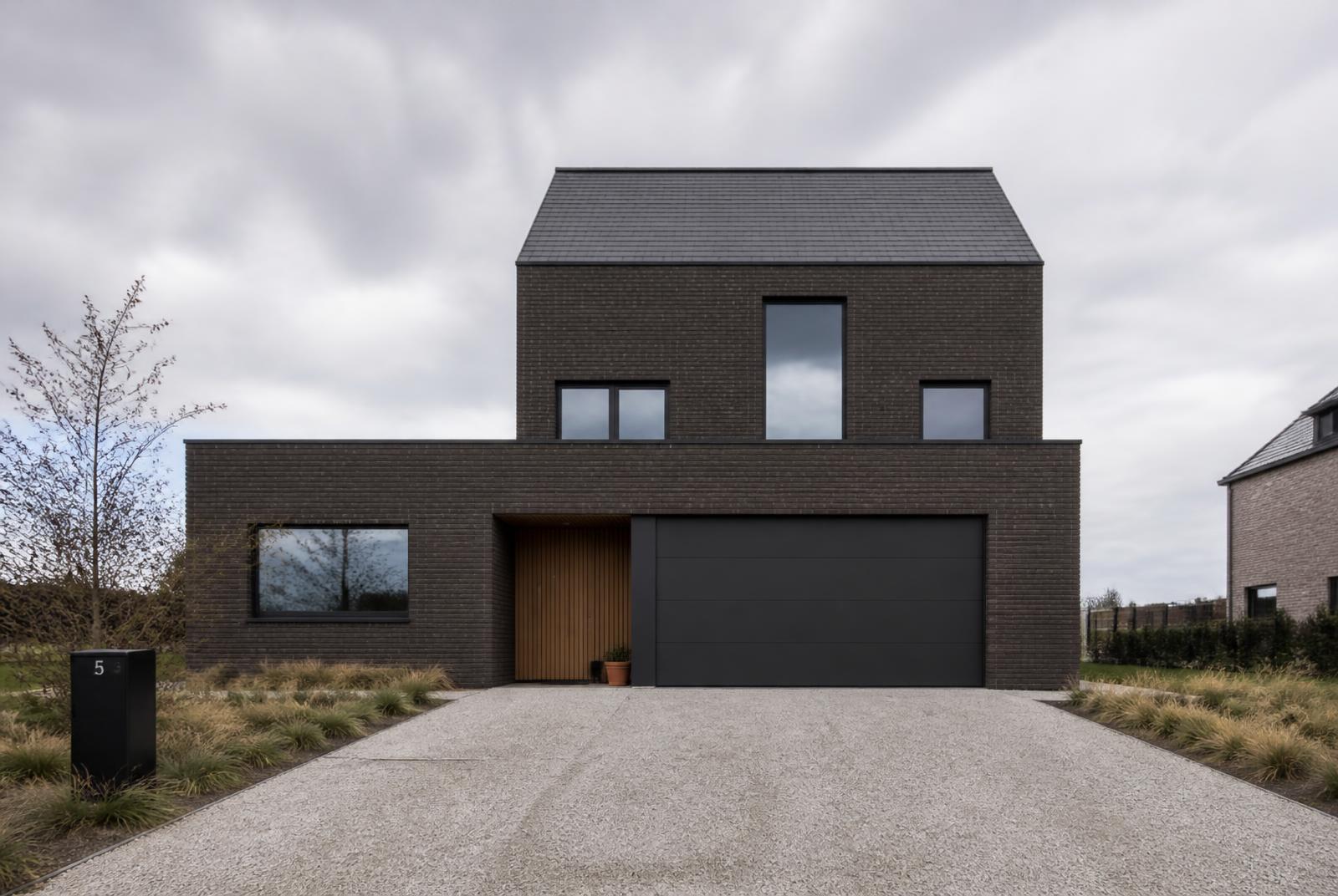 Afgewerkte nieuwbouwwoning met donkere gevelsteen en aluminium ramen